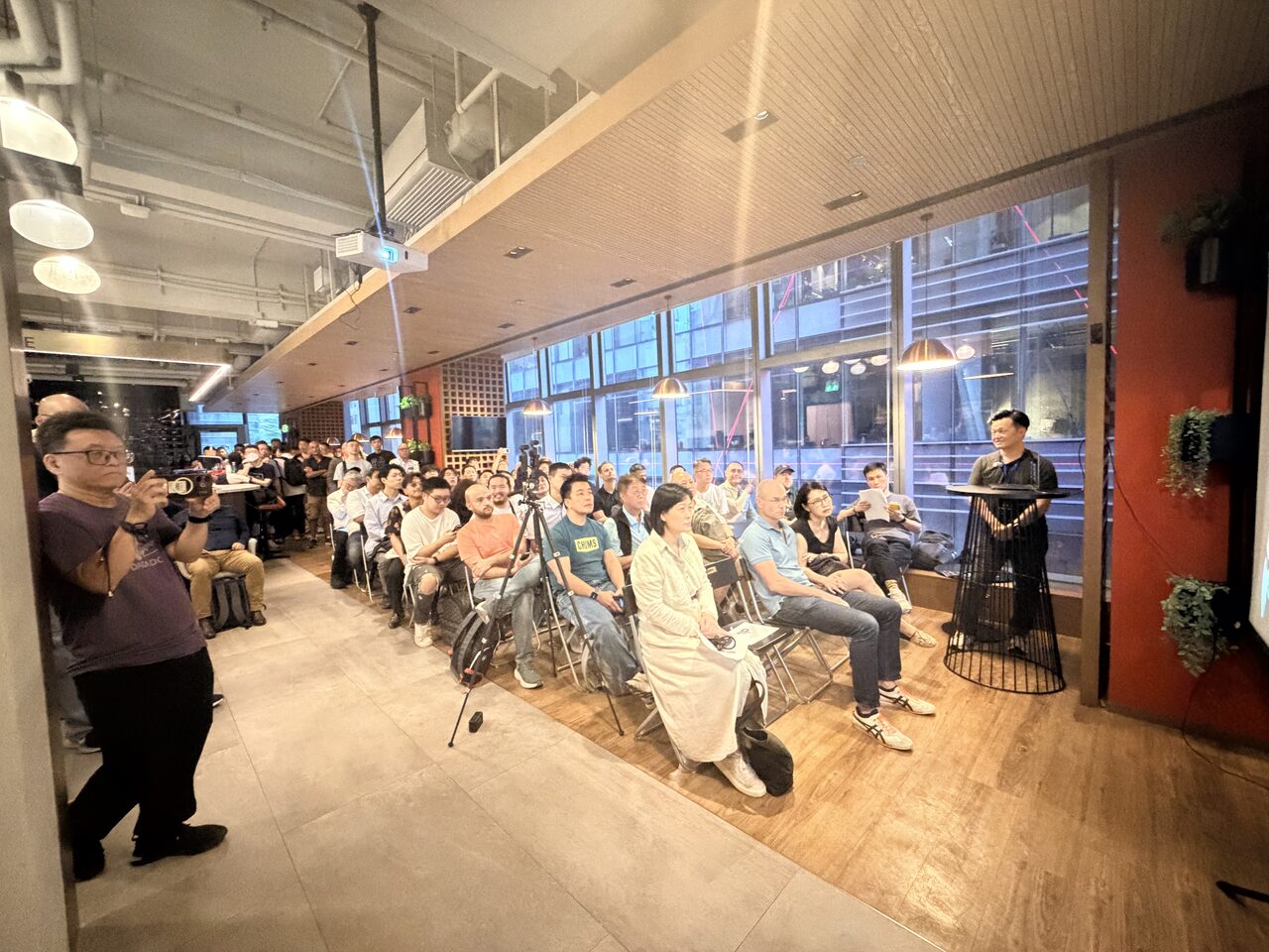 The full audience seated and watching, the Hong Kong skyline through the windows